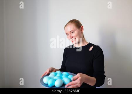 Smiling woman presenting colored eggs, Easter celebration and home tradition concept. Stock Photo