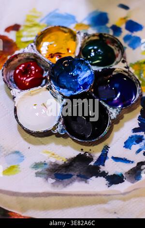 Watercolor palette with colorful pigments on paper showing artistic process, creativity and paint mixing in studio. Stock Photo