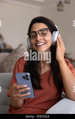 Smiling woman enjoying music through wireless headphones Stock Photo