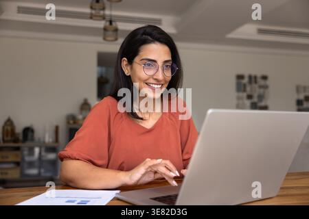 Focused woman working on laptop at home Stock Photo