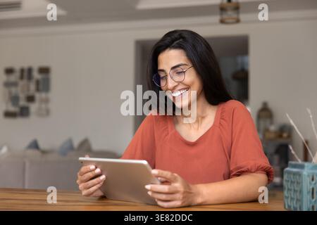 Smiling woman using digital tablet at home Stock Photo