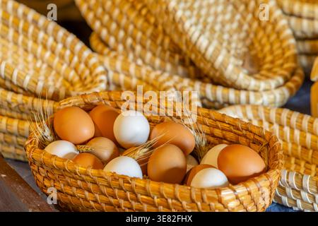 Farm fresh brown and white chicken eggs in a traditional wicker basket with wheat Stock Photo