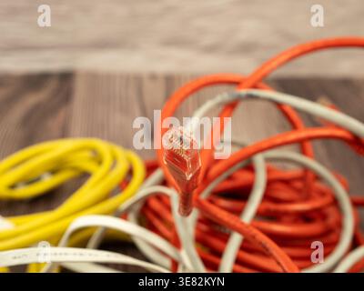 Macro shot of an orange RJ45 network cable plug with a tangled mess of colorful cat5 cables Stock Photo