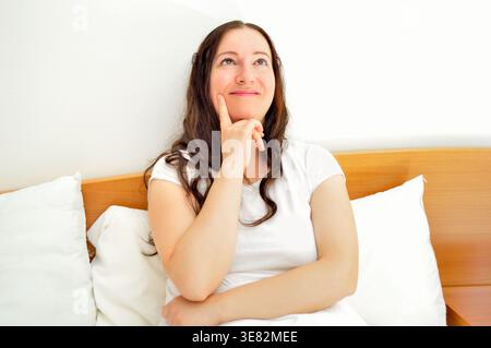 close up of woman thinking and looking up at bedroom Stock Photo
