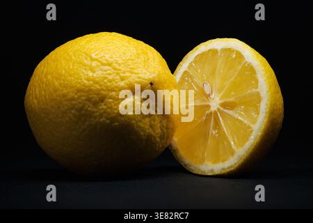 Lemon Whole and Half Macro Close Up – Fresh Citrus on Black Background Studio Lighting Stock Photo