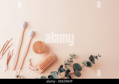 Natural bamboo toothbrushes and eco friendly hygiene accessories on soft beige background with eucalyptus branch. Minimalist flat lay composition. Top Stock Photo
