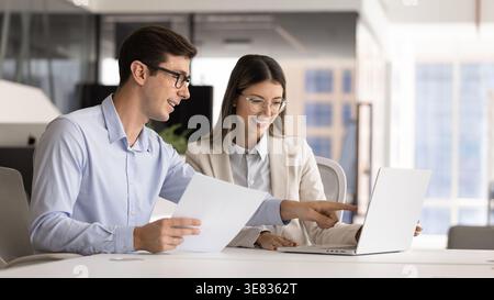 Business colleagues analyzing data together on laptop Stock Photo