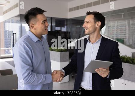 Client shaking hands with consultant holding a digital tablet in office Stock Photo
