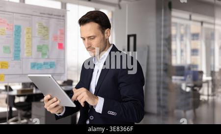 Focused mid adult businessman working on digital pad in office Stock Photo