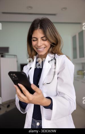 Happy therapist woman using smartphone during break in workplace Stock Photo