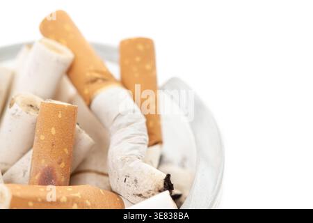 Bunch used cigarettes inside ashtray isolated white background macro corner view Stock Photo