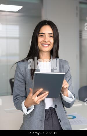Portrait of smiling businesswoman holding digital tablet, looking at camera Stock Photo