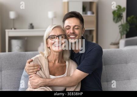 Loving young adult man embracing his older smiling mother Stock Photo
