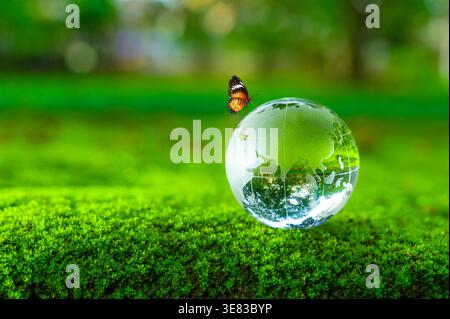 The globe is made of glass and sits on green moss. The concept is related to Earth Day, World Environment Day, and environmental conservation. Stock Photo