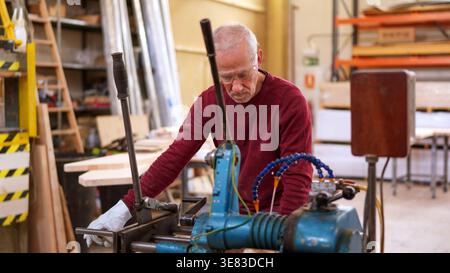 Senior carpenter threading a steel bar in workshop Stock Photo