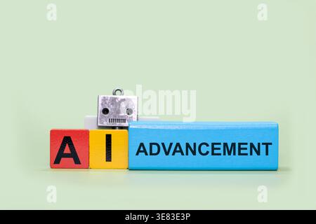 Toy robot head and colorful wooden blocks spelling Advancement of AI Stock Photo