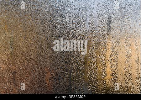Glass surface covered with condensation and scattered droplets, condensation creating calm abstract background. Moisture pattern reflects cold air, fr Stock Photo
