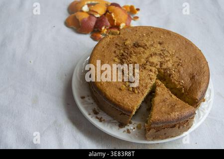 Traditional sponge cake with orange zest on a white plate with peel in the background Stock Photo