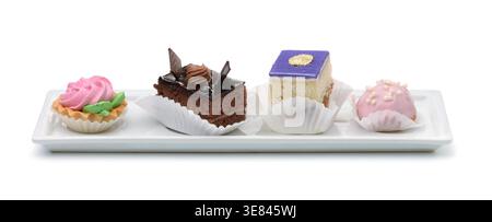 Four different mini cakes on ceramic plate isolated on white Stock Photo