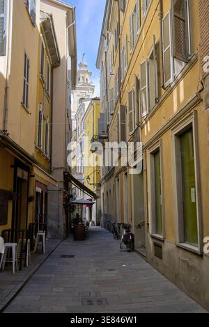 Italian alleyway in the historic city center of parma, emilia-romagna, featuring old architecture and a distant church tower Stock Photo