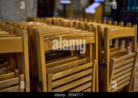 A stack of wooden folding chairs stored neatly indoors. Stock Photo