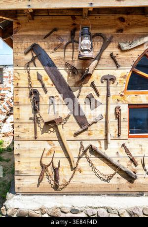 Assorted old rusty metal work tools on wooden wall. Vintage rusty household tools hang on the wall Stock Photo