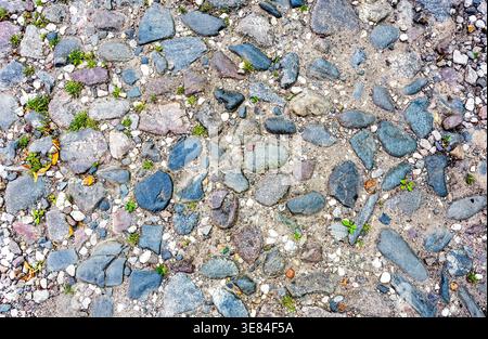 Rough cobblestone pavement on the road as creative background texture. Natural stones as background. Stone pavement texture Stock Photo