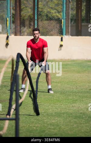 Middle Eastern man training outdoors with battle ropes in a CrossFit style fitness workout Stock Photo