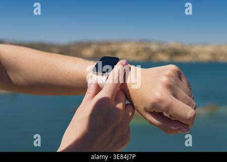 Person interacting with a wearable device on wrist, using modern technology for managing time, monitoring health, and staying connected in a natural e Stock Photo
