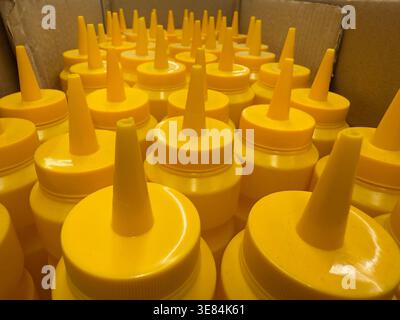 Mustard bottles neatly organized inside a cardboard box, viewed from above. Mobile photo Stock Photo
