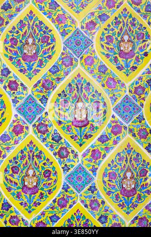 Colorful thai ornamental pattern with lotus and floral motifs in diamond frames, repeating wallpaper design in yellow, blue and purple, traditional te Stock Photo