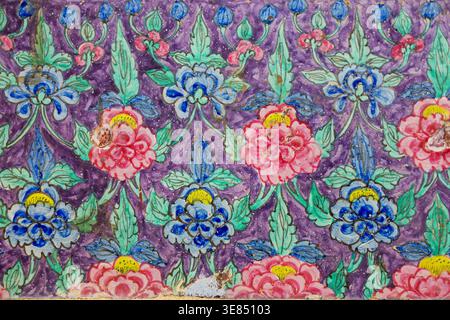 Hand-painted floral pattern with stylized blue and pink flowers and green leaves on textured purple background, repeating ornamental motif, vintage fo Stock Photo