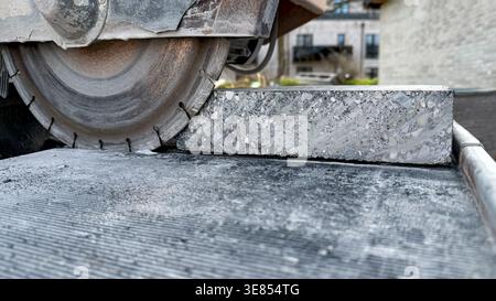 Concrete cutting saw blade in action on a block of concrete, showcasing the cutting process and machinery in a construction site environment Stock Photo