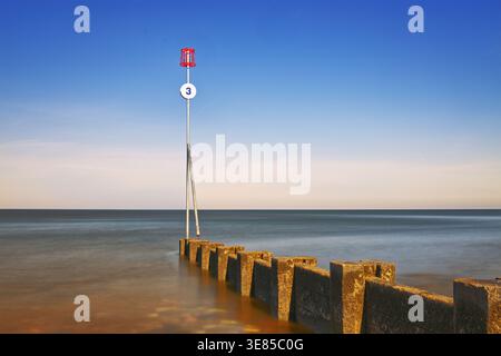 Hunstanton, Norfolk, England, UK - Long exposure shot of a concrete  groyne surrounded by the seawater of The Wash on Hunstanton beach at sunrise Stock Photo