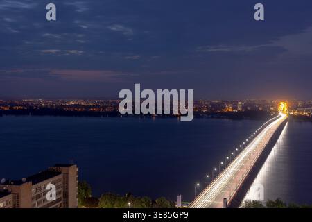 Aerial view of a long bridge illuminated at dusk stretching across the ...