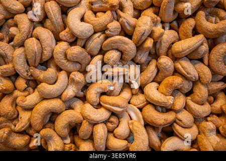 Full frame background of roasted cashew nuts with natural texture and warm brown color. Stock Photo