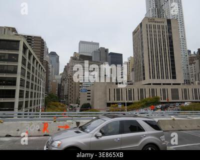 New York, USA - October 24, 2012 A high-angle view from a bridge showing a silver SUV in the foreground with various office and residential buildings Stock Photo
