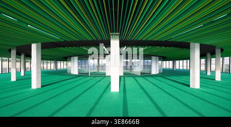 Wide-angle view of an empty modern office building floor with green ceiling slats and carpet, white columns, and panoramic windows, creating a spaciou Stock Photo