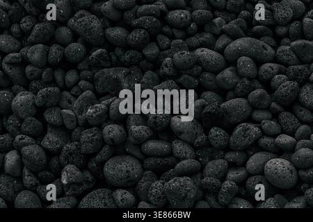 Close-up of black volcanic pebbles forming a natural texture on La Palma, Canary Islands. Dark basalt stones create a rugged beach background with por Stock Photo