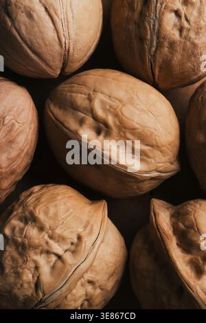Macro close-up of whole walnuts in shells on a dark background, showing natural texture and earthy tones. Ideal for food, nutrition, harvest, and heal Stock Photo