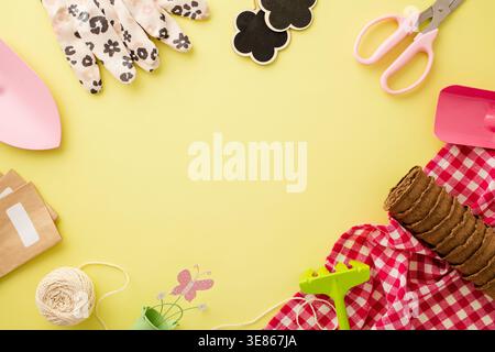 Flat lay on a bright yellow background with gardening equipment and tools, including gloves, scissors, string, seed packets and pots. Stock Photo