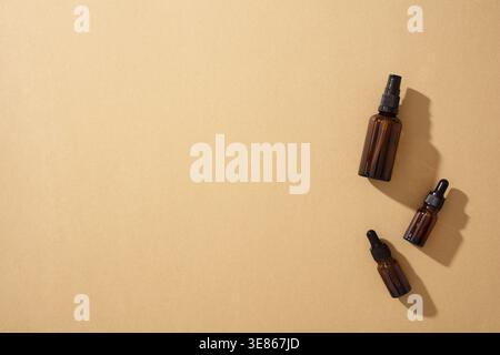 Three brown glass bottles for natural cosmetics on a brown background, emphasizing zero waste and eco-friendly skincare. Ideal for organic beauty prod Stock Photo