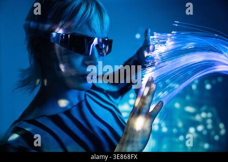 A young woman in a futuristic environment interacts with glowing fiber optics, embodying the essence of the metaverse. The scene is vibrant, dynamic, Stock Photo