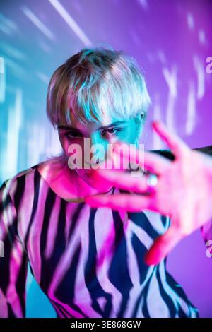 A young woman reaches forward, immersed in a vibrant, futuristic metaverse. The dynamic blend of colors reflects the digital age's innovative spirit a Stock Photo