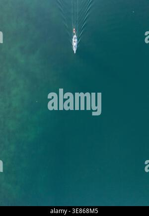 Aerial view of a boat sailing on the azure waters of Lake Geneva, captured by drone. The calm, expansive water offers a serene backdrop, highlighting Stock Photo