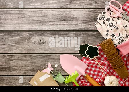 A collection of gardening tools and accessories on a rustic wooden table, including a trowel, rake, gloves, and peat pots, ideal for spring gardening Stock Photo
