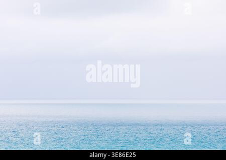 A minimalist photograph capturing a solitary yacht on the calm, blue waters off the coast of Villajoyosa. The sky above is very bright and hazy, creat Stock Photo