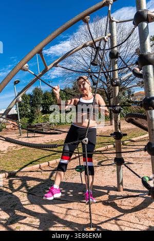 Senior woman training on climbing frame in park Stock Photo