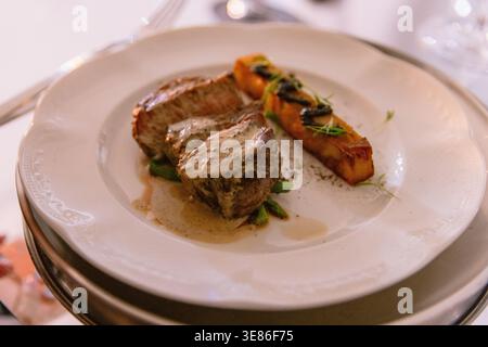 Gourmet plated beef steak with creamy sauce and roasted vegetables in fine dining restaurant Stock Photo