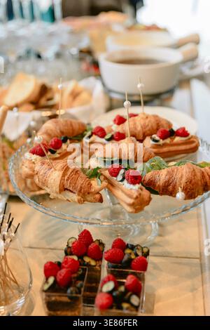 Elegant catering table with croissants, desserts and fresh berries for festive buffet or brunch Stock Photo